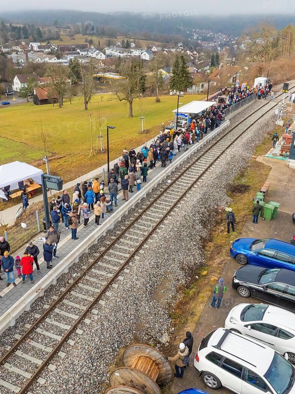 People stand next to parked cars at a railway station in rural surroundings, opening of the Hermann Hesse Railway, Calw, Germany