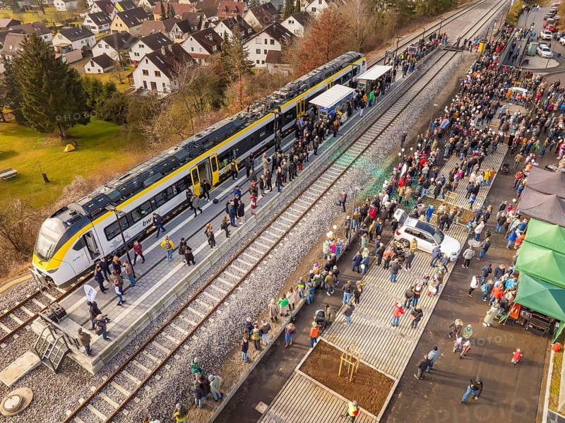 Large groups of people receive a train on the platform, surrounded by city and nature, opening of the Hermann Hesse Railway, Calw, Germany