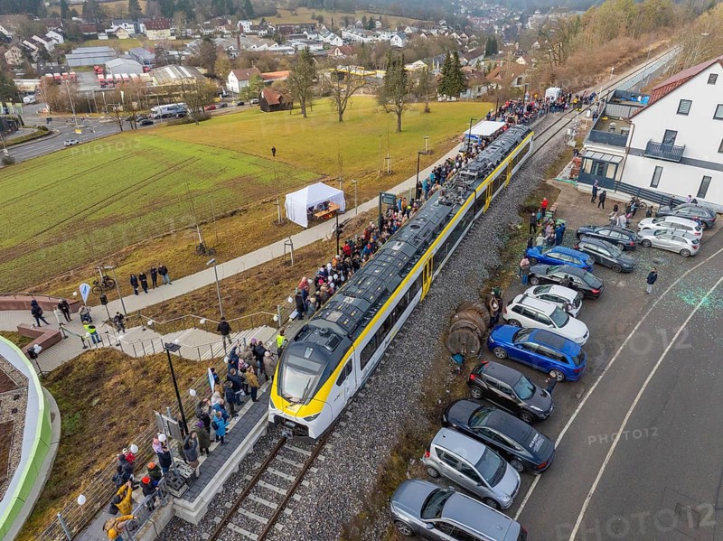 Train at a train station with people waiting and parked cars in a rural urban landscape, opening of the Hermann Hesse Railway, Calw, Germany