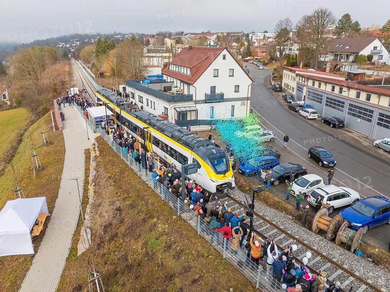 Aerial view of a train on a route with people and rain of confetti next to buildings during an event, opening of the Hermann Hesse Railway, Calw, Germany
