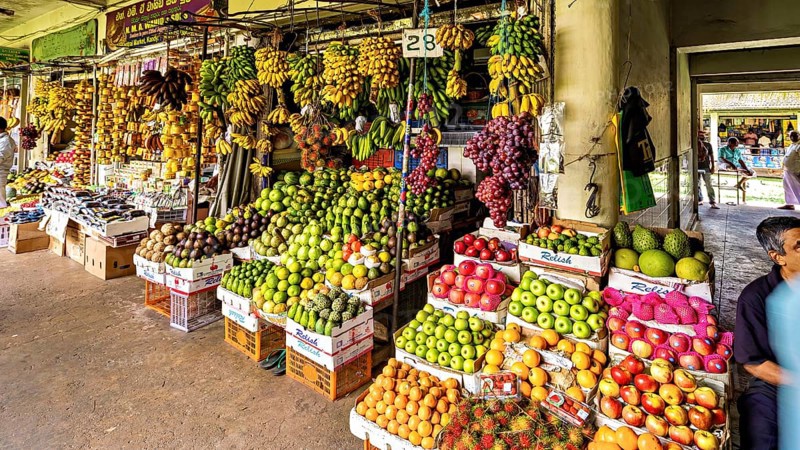 Diverse market stand with plenty of fruit, carefully stacked in a pavilion, The old market halls of Kandy in Sri Lanka