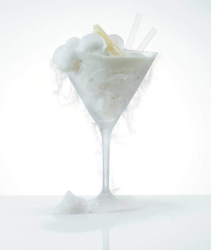 Lemon ice cream in a frosted cocktail glass, the cold creates ice fog on the glass, studio shot against a white background