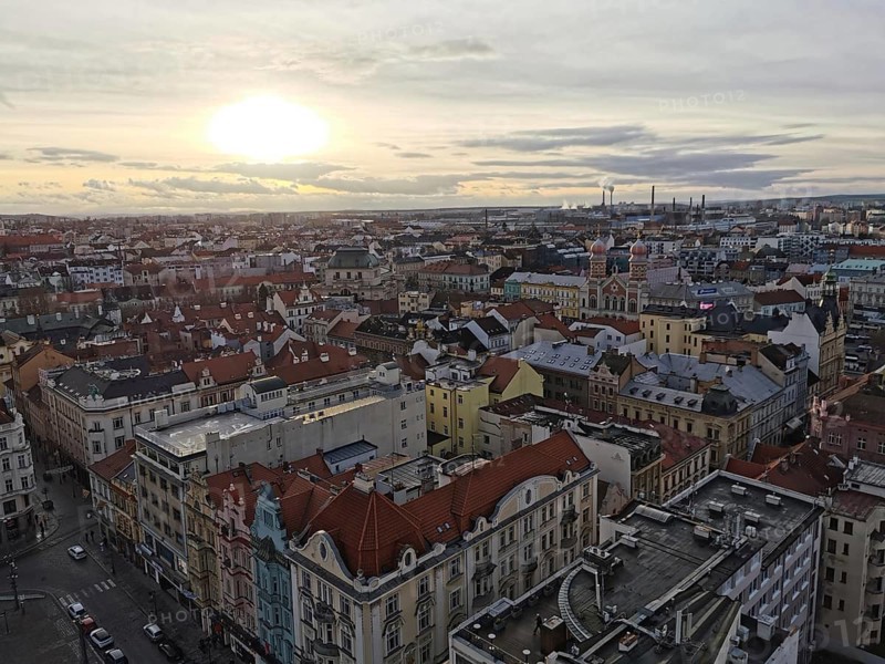Extensive view of urban rooftops at sunset with industry on the horizon, Pilsen, Czech Republic