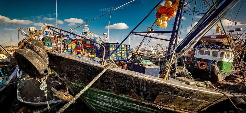 Detailed scene with colorful fishing boats and lively harbor atmosphere when the sun is shining in bright colors, Essaouira, Morocco