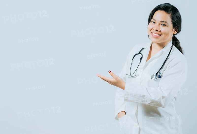 Smiling asian female doctor showing empty space isolated. Young asian doctor presenting something isolated
