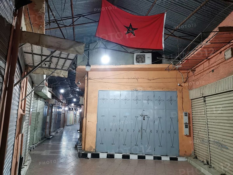 Medina during Ramadan Empty market alley at night with locked shops and a Moroccan flag, Morocco