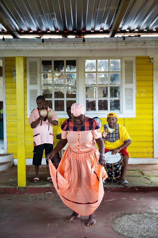 Guatemalan woman in traditional dress singing and dancing, men playing music in the back, Garifuna people, Livingston, Izabal Department, Guatemala