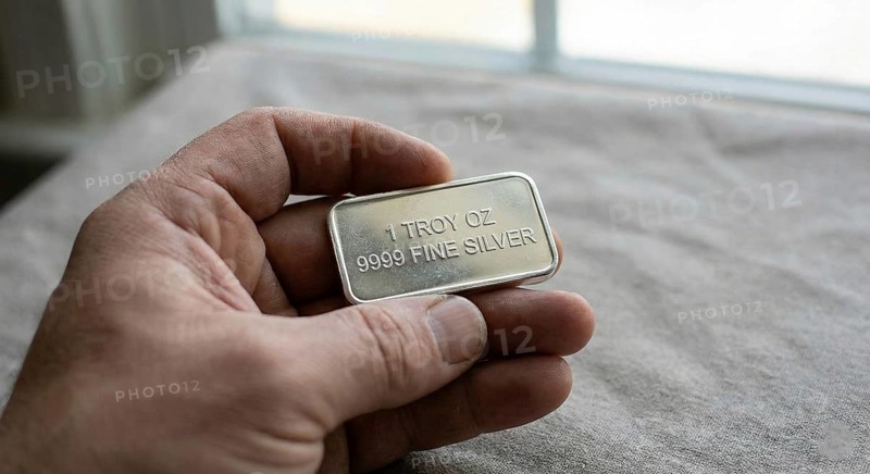 Fine silver bar, with neatly stacked silver bullion bars arranged behind it, symbolising precious metal investment, wealth preservation, and commodity trading, AI generated