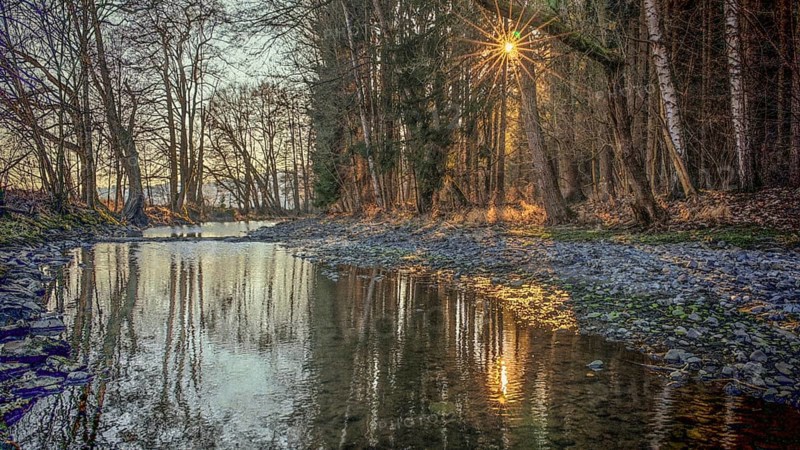 Romantic river landscape at sunset with rays of light through the trees and a peaceful atmosphere, Upper Franconia, Germany