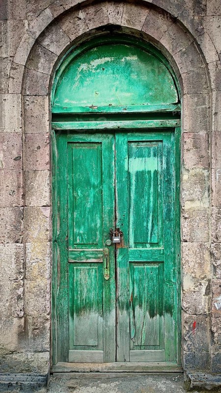 Locked green wooden door with a stone arch, rustic charm
