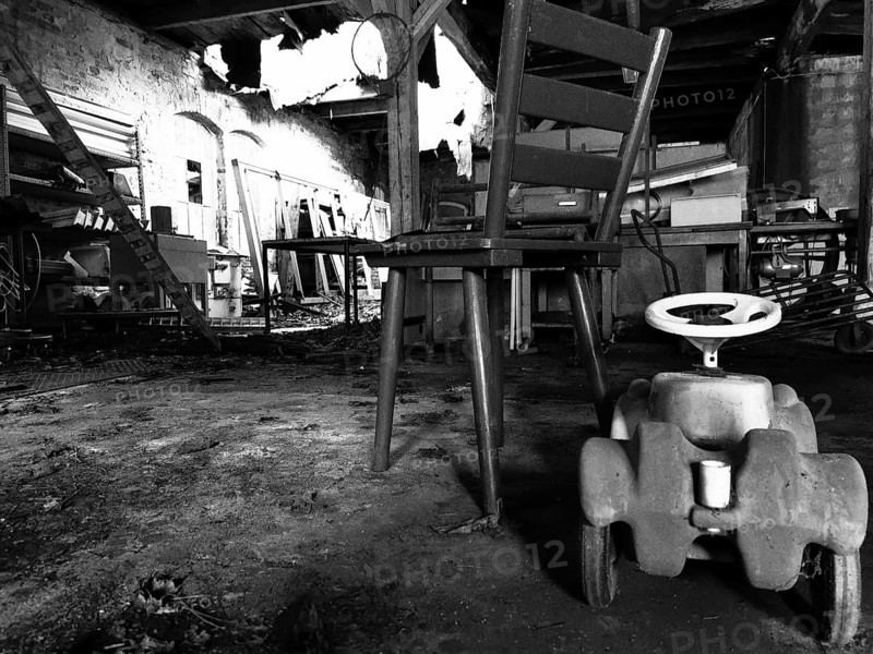 Abandoned industrial space with an old chair and a toy car on the floor, black and white, Upper Franconia