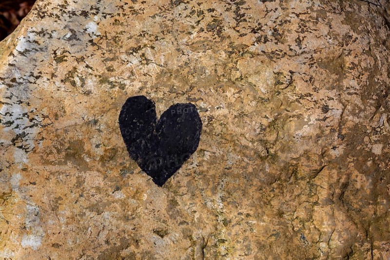 Close-up of painted black heart symbol on tanned nuanced rock surface, Quebec, Canada