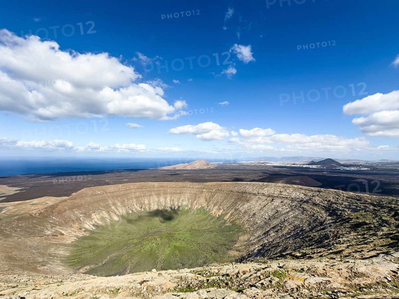 View of the Caldera Blanca volcano cauldron against blue sky with white clouds, Mancha Blanca, Lanzarote, Canary Islands, Spain