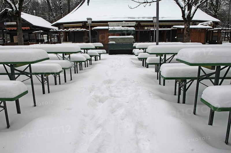 Winter in the English Garden, snow-covered beer garden tables and benches, Munich, Bavaria, Germany