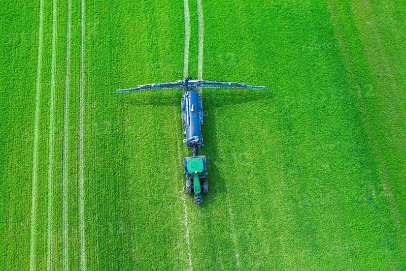Aerial view over tractor towed liquid manure spreader, slurry spreader enabling the fertilization of arable land by distributing slurry in spring
