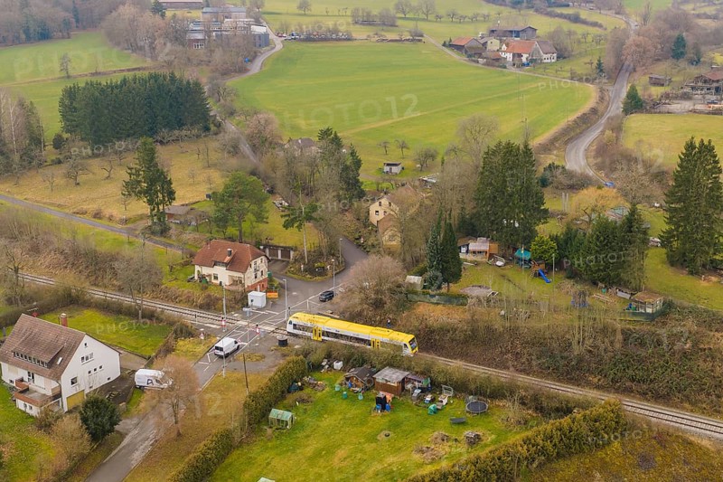 Rural landscape with individual houses, fields and a yellow train on the tracks, acceptance of the Hermann Hesse Railway, Calw, Black Forest, Germany