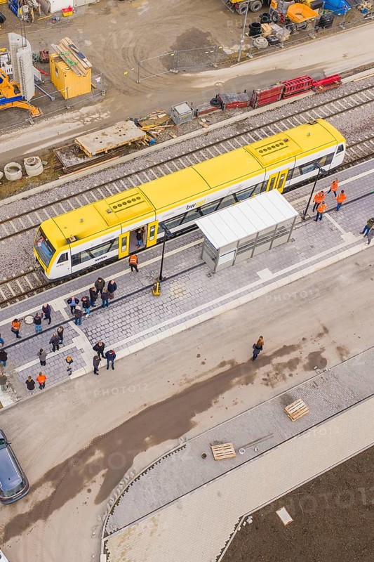 A bird's eye view of a yellow train at a train station with people, taking the Hermann Hesse Railway, Calw, Black Forest, Germany