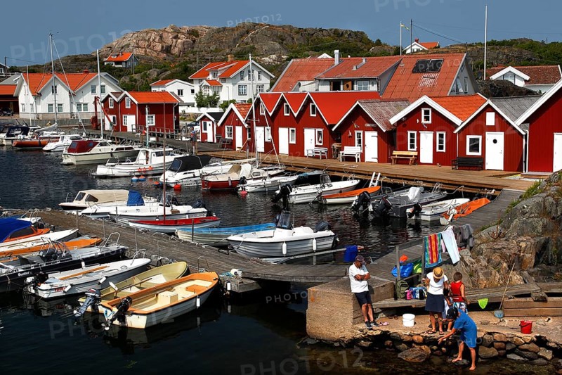 Red wooden houses on a lively harbour full of boats in idyllic surroundings, Klädesholmen, Västra Götaland, Sweden