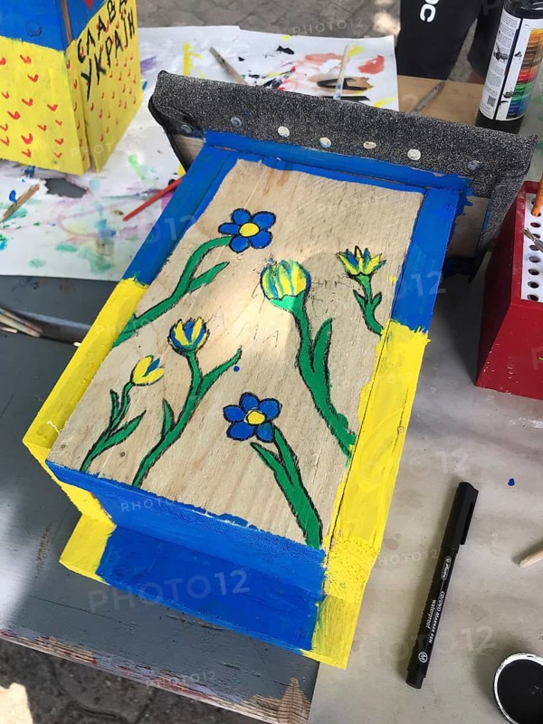 Lower Saxony, Germany, painted bird house in blue and yellow with flowers. Ukrainian students' creative craft project with spring-like design