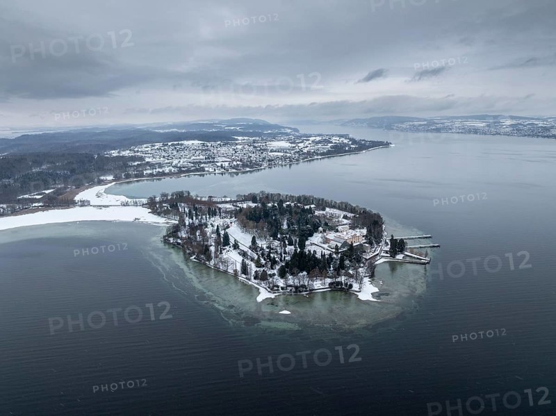 The wintry and snowy Mainau island in Lake Constance with the pier and the baroque Mainau Castle, built between 1739 and 1746, behind it the village of Litzelstetten, aerial view, district of Konstanz, Baden-Württemberg, Germany