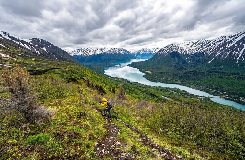 Climbers on a hiking trail, Slaughter Ridge Trail, view of snowy mountains in spring and turquoise blue Kenai Lake Lake, Cooper Landing, Kenai Peninsula, Alaska, USA