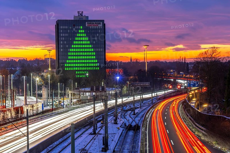 Autobahn A40, Ruhrschnellweg, between Essen and Mülheim an der Ruhr, evening traffic in winter, former, now vacant Stinnes high-rise building, at the Rhine-Ruhr Center, showing a green Christmas tree from illuminated windows at Christmas time, North Rhine-Westphalia, Germany