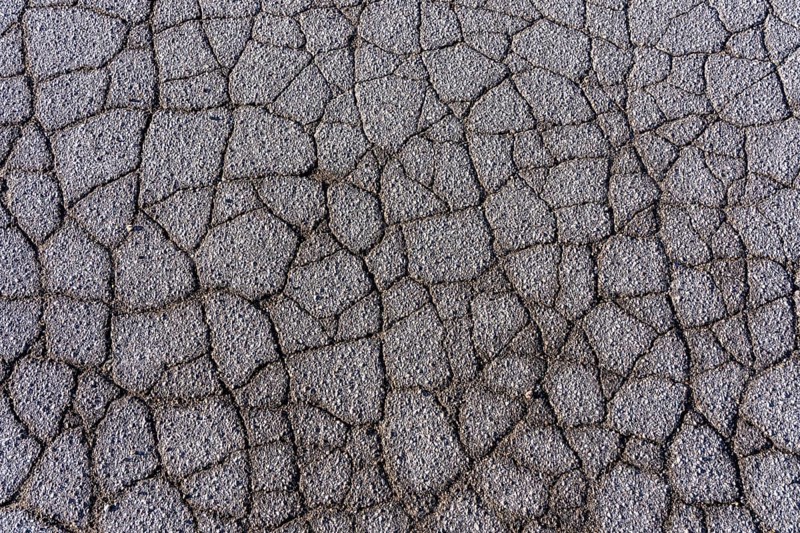 Asphalt surface, floor, with many small cracks, roadway, parking lot