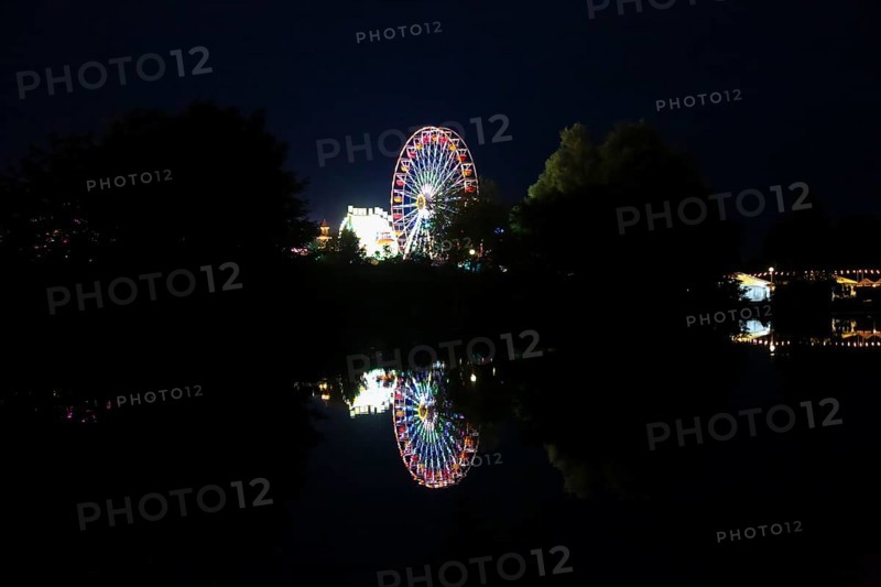 Fairground in Ulm Friedrichsau at night, folk festival, hustle and bustle, fair, Ferris wheel, amusement park, amusement attraction, ride, artificial light, darkness, reflection in natural lake, Ausee, Ferris wheel, Ulm, Baden-Württemberg, Germany