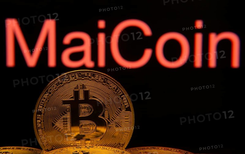 Dhaka, Bangladesh- 03 Sep 2025: Close-up of Bitcoin coins with the MaiCoin logo visible on a screen in the background