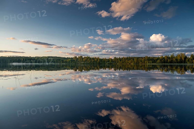 Clouds reflected on the water surface, forest lake, evening mood, at Sunne, Sweden