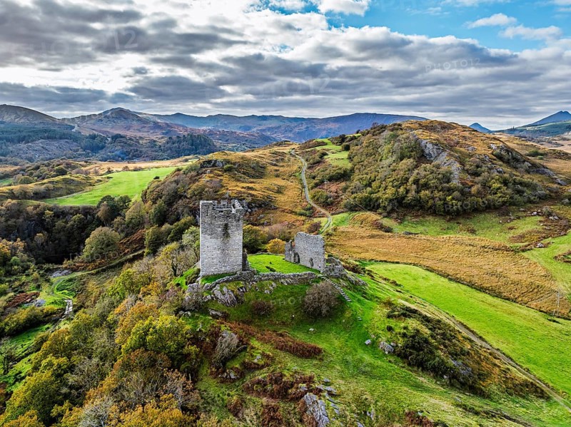 Autumn colours over Castell Dolwyddelan and Eryri Mountains from a drone, Snowdonia, Conwy County Borough, Wales, England, United Kingdom