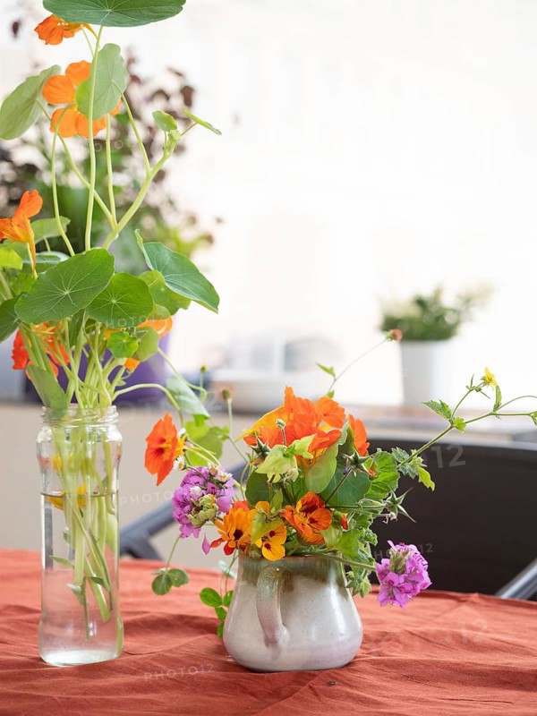 Florist arranging nasturtiums and verbenas in a ceramic jug during an ikebana workshop