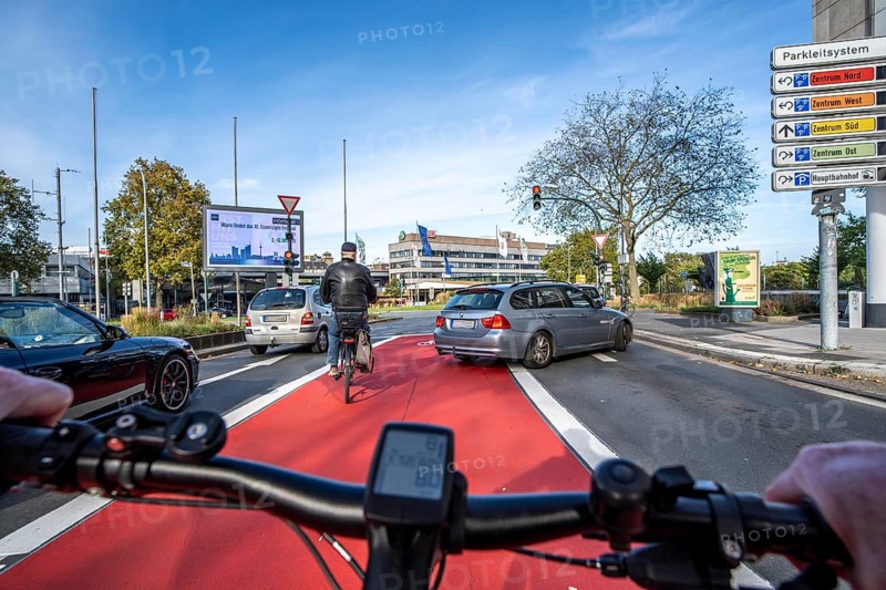 Riding a bike in a bike lane, marked in red to attract the attention of motorists, between 2 lanes, Huyssenallee, in front of Europaplatz, in the city centre of Essen, North Rhine-Westphalia, Germany
