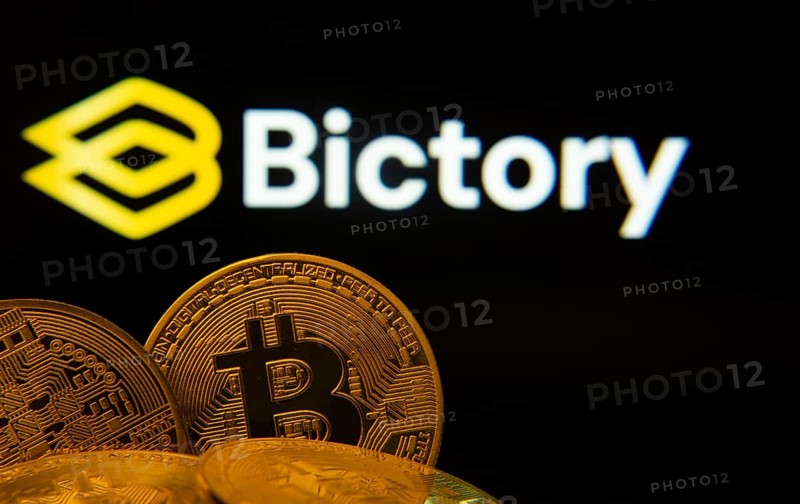 Dhaka, Bangladesh- 09 Sep 2025: Close-up of Bitcoin coins with the Bictory logo visible on a screen in the background