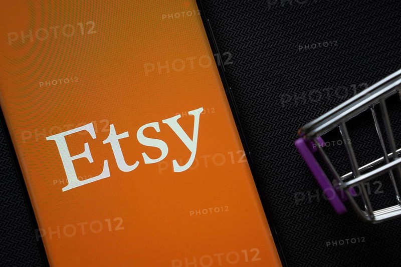Dhaka, Bangladesh- 03 July 2025: A smartphone displaying the Etsy logo next to a miniature shopping cart on a background