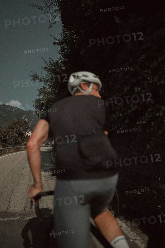 Young man riding a racing bike on Lake Garda. Sunny weather and dolce vita