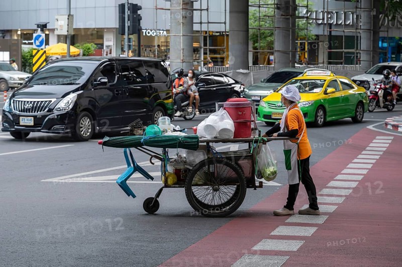 Street crossing woman with cookshop, Bangkok, Thailand