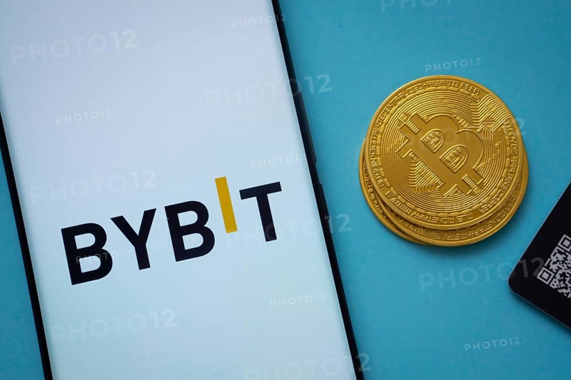 Dhaka, Bangladesh- 15 July 2025: Bybit logo on smartphone screen near Bitcoin coin and QR code on blue background
