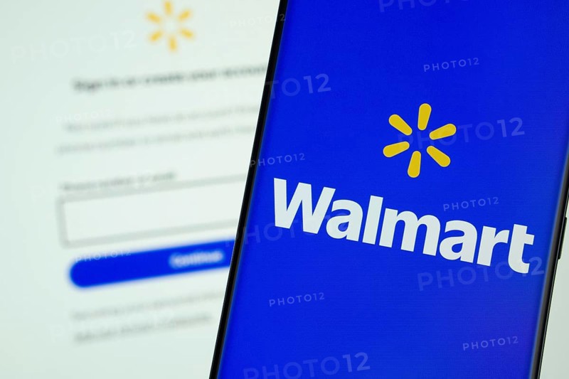 Dhaka, Bangladesh- 15 July 2025: Walmart logo is displayed on a smartphone screen, with the walmart login page visible on a computer screen in the background