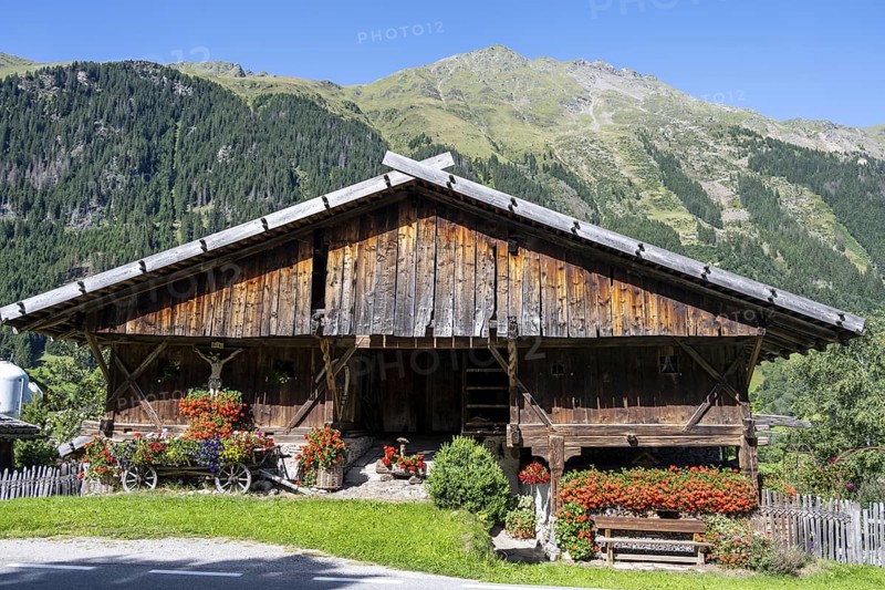 Colourful floral decorations and crucifix at a rustic alpine hut, Ridnauntal, South Tyrol, Italy