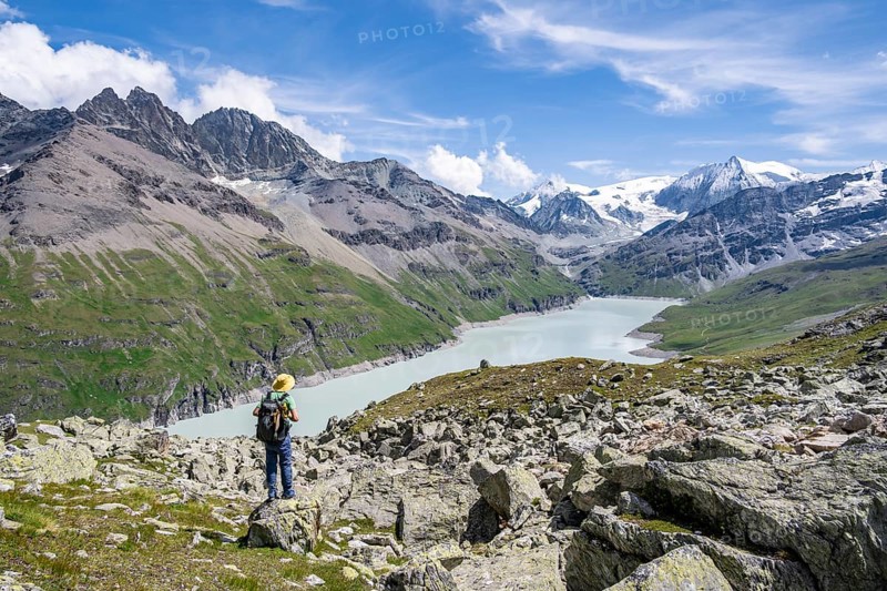 Mountaineer on a hiking trail at a blue mountain lake, reservoir Lac des Dix, behind mountain peak Mont Blanc de Cheilon, Hérménence, Valais Alps, Valais, Switzerland
