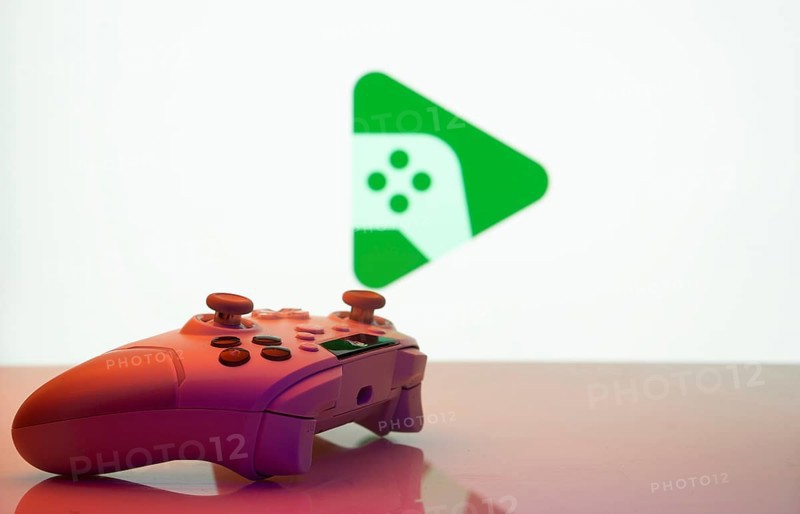 A close-up of a gamepad with the Google Play Games seen on screen in the background