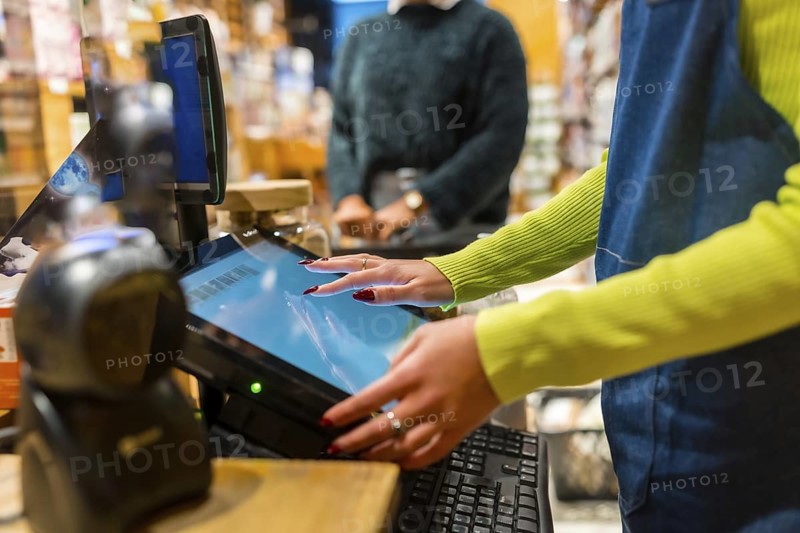 Salesperson using a touch screen cash register in an organic supermarket, selling natural and gluten free products