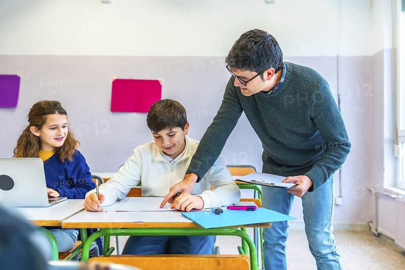 Teacher assisting students in the classroom, explaining concepts and correcting exercises while fostering a supportive learning environment