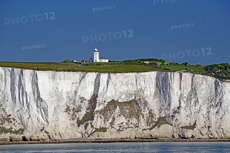 Chalk cliffs with small lighthouse on green grass under blue sky, Dover, Kent, England, Great Britain