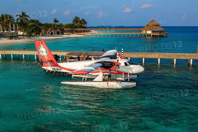 Seaplane floating in lagoon is moored at pier jetty of Maldives island Filaidhoo Reethi Faru, Raa Atoll, Maldives
