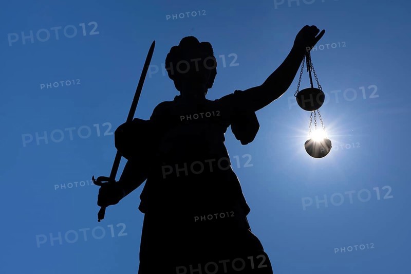 The silhouette of the Justitia statue on the Römerberg in Frankfurt am Main is silhouetted against the sun. It looks as if the sun is lying in her scales of justice, Frankfurt am Main, Hesse, Germany