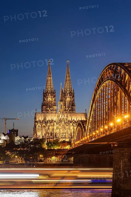 Cologne Cathedral, illuminated in the evening. Hohenzollern Bridge, railway bridge over the Rhine. City view of Cologne, North Rhine-Westphalia, Germany