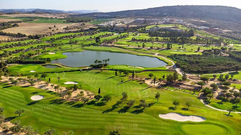 Wide aerial view of a luxury golf course with green grass and a lake