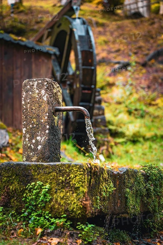 Historic Streinbrunnen fountain with mill wheel in autumn, Bad Wildbad, Kurpark, Black Forest, Germany